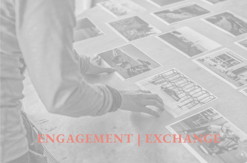 Explore Engagement and Exchange: participants examine photographic materials around a table, introducing talks, workshops, mentoring and cultural projects.