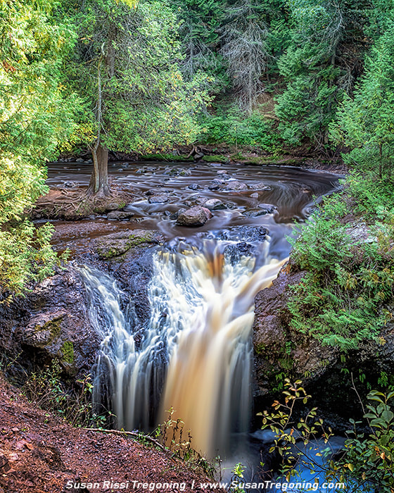 A long‑exposure view of Snake Pit Falls in Amnicon Falls State Park, where the Amnicon River drops about 25 feet straight into a narrow, rocky gorge surrounded by dense forest. The timed exposure creates silky, blurred water.