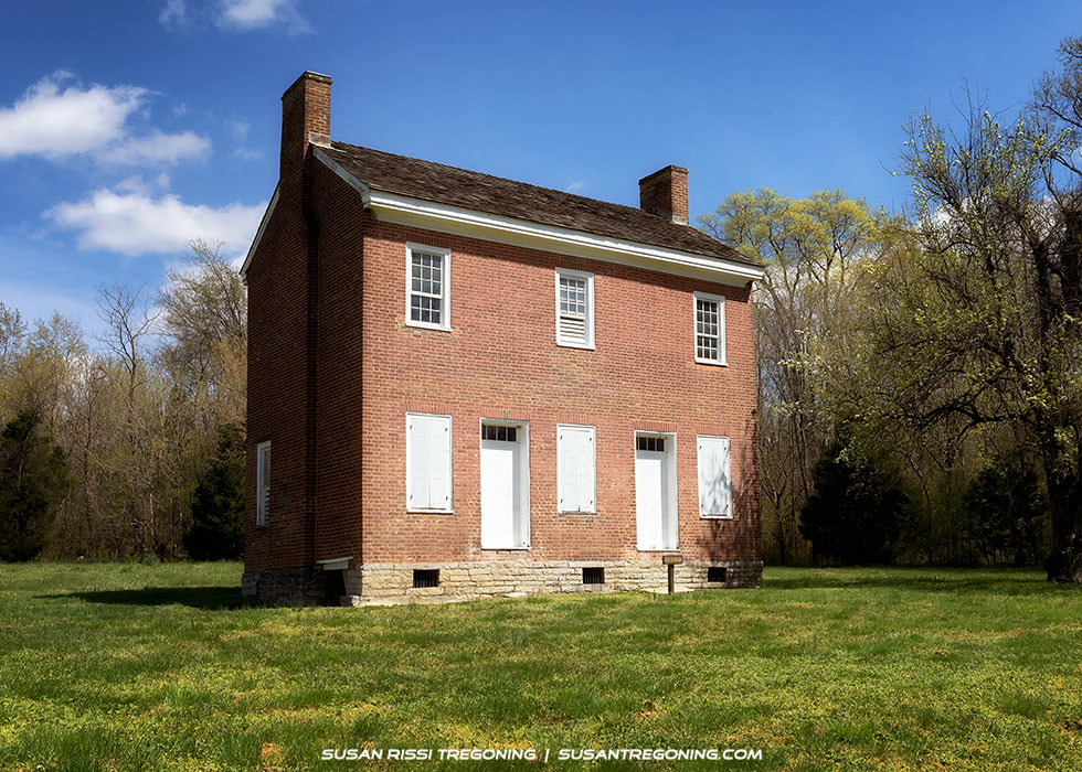 The Gordon House, a two‑story brick home built in 1817–1818, standing beside an open grassy area with trees in the background along the Natchez Trace Parkway.