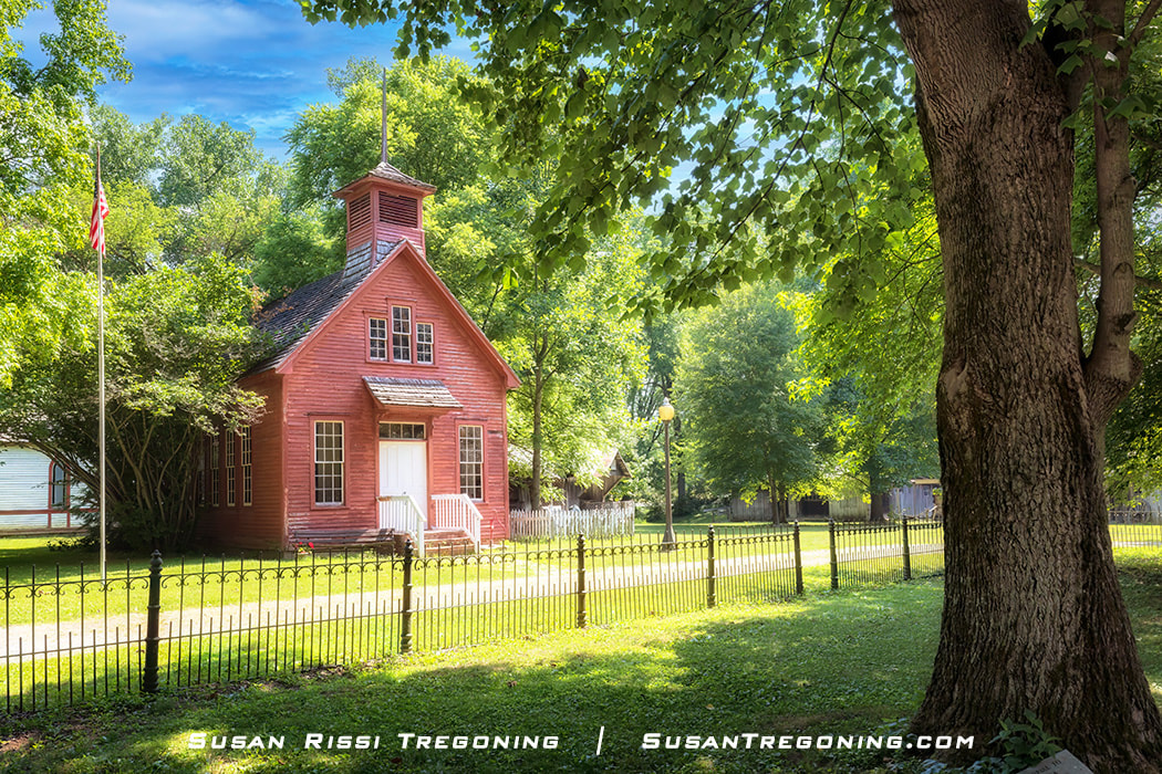 The little red 1923 Huxford one-room schoolhouse set in the lush green summer folliage on the grounds of Billie Creek Village in Rockville, Indiana. 