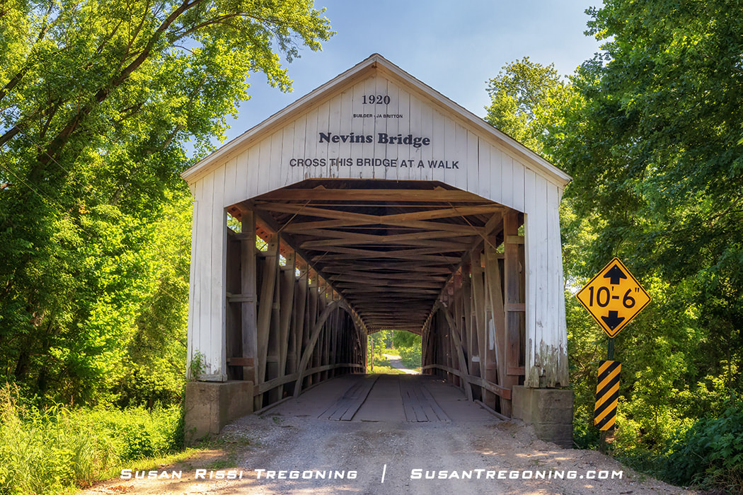 Nevins Covered Bridge, built in 1920 as the final covered bridge constructed by J.A. Britton and the last historic bridge built in Parke County, Indiana, shown surrounded by dense green trees with a clearance sign beside the entrance.
