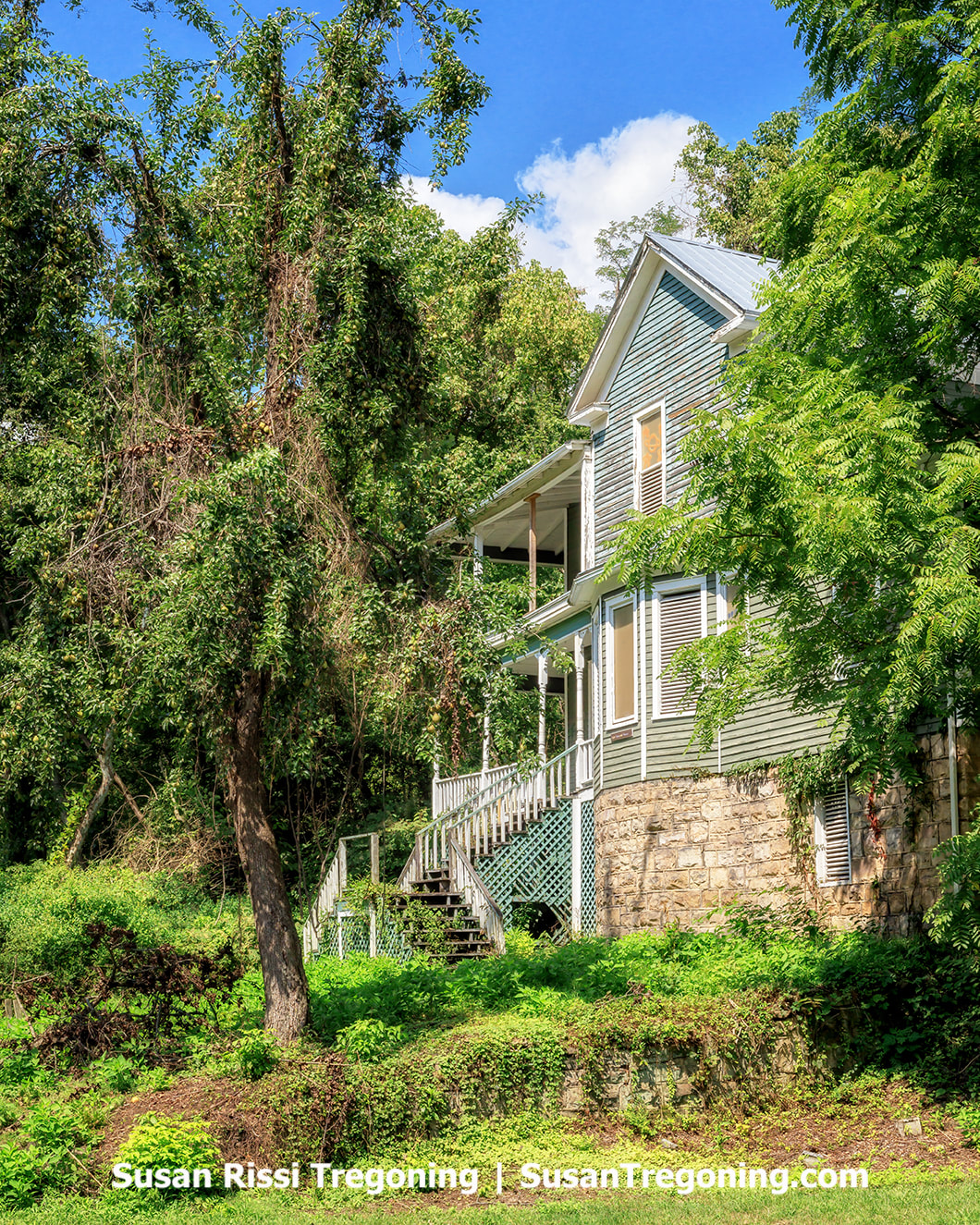 A large historic house built around 1900, known as Fatty Lipcomb’s Guest House, standing on the floodplain at the west end of Thurmond. The two‑story structure sits in front of the railroad tracks at the base of the mountain and is one of the few remaining historic homes in town.
