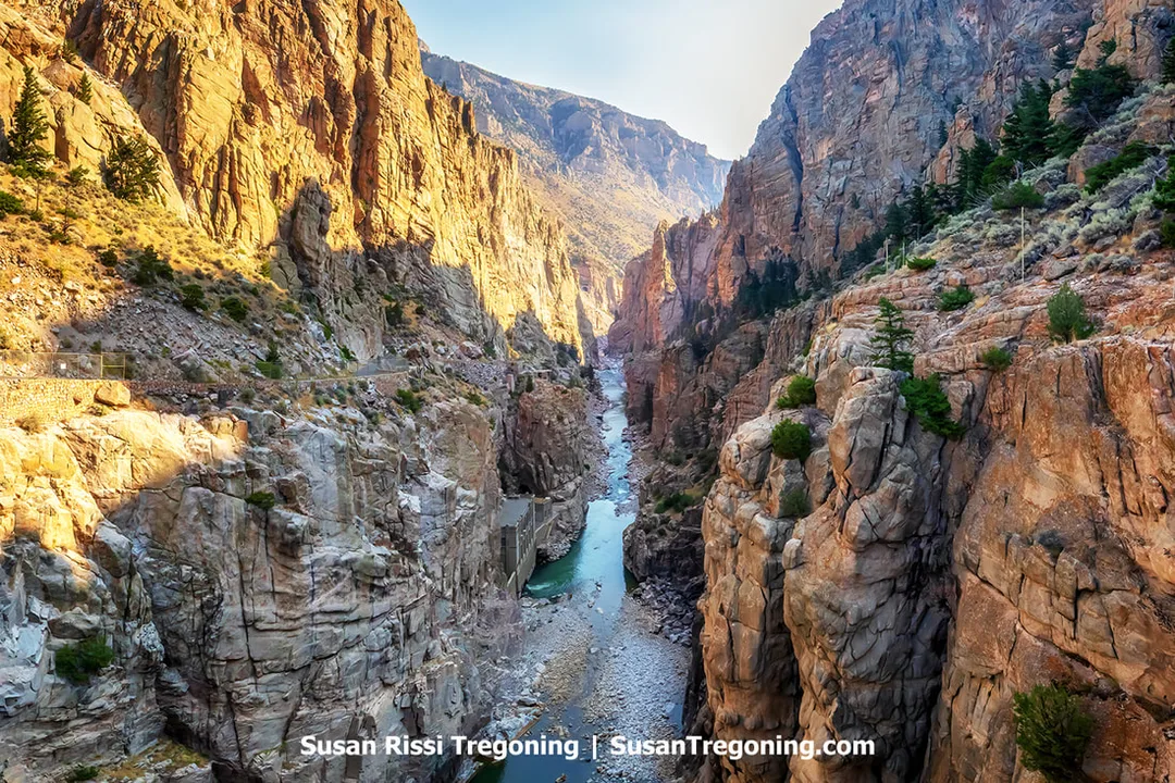   
A deep rocky canyon with steep, rugged cliffs on both sides and a narrow river running through the bottom. Sunlit sections of the canyon contrast with darker shadowed areas, and sparse vegetation clings to the slopes.