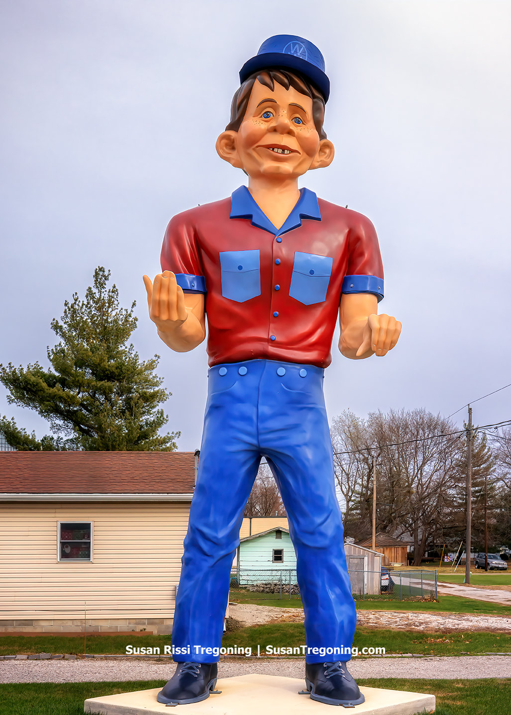 A Muffler Man‑style fiberglass giant known as the Snerd stands outdoors. The figure has a comical grin reminiscent of Alfred E. Neuman from Mad Magazine. It was likely produced between 1966 and 1970 and shows evidence of past damage and repair, including missing or replaced sections. The giant is associated with earlier uses at a miniature golf course, a hot dog stand, and later the Wagon Wheel Bar in Madison, Ohio.