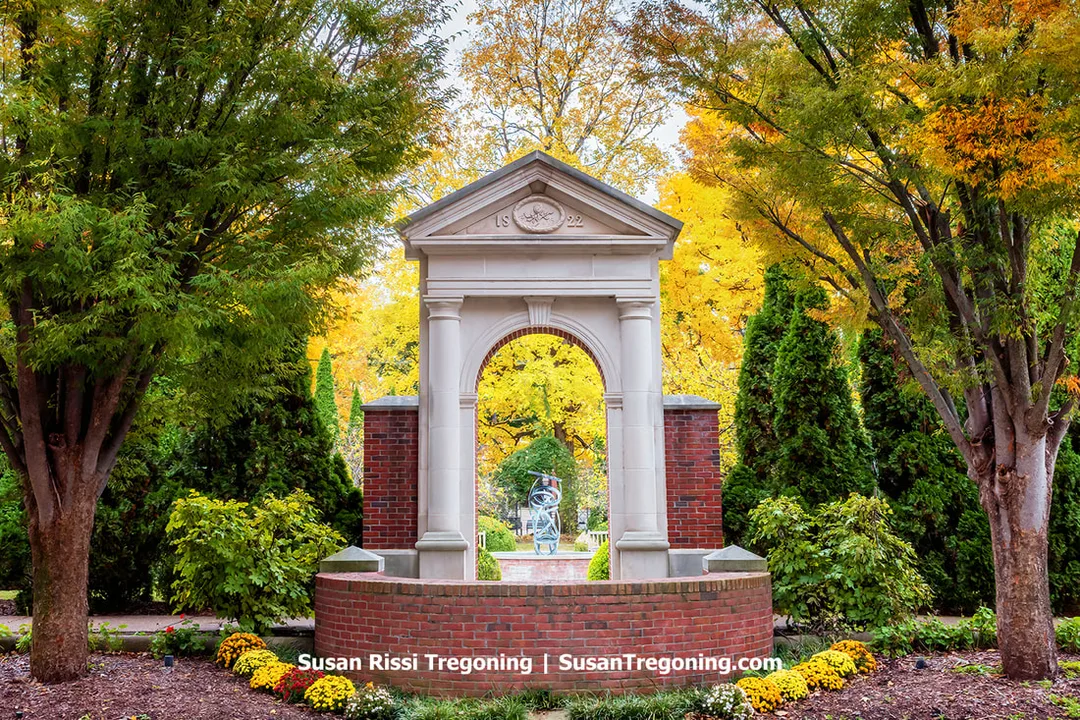 The 1822 stone archway rises above autumn gardens in Church Park, framing the modern sculpture beyond it. Once part of the early Harmonist community, the arch now stands as a symbolic threshold between New Harmony’s utopian past and its enduring spirit of renewal.