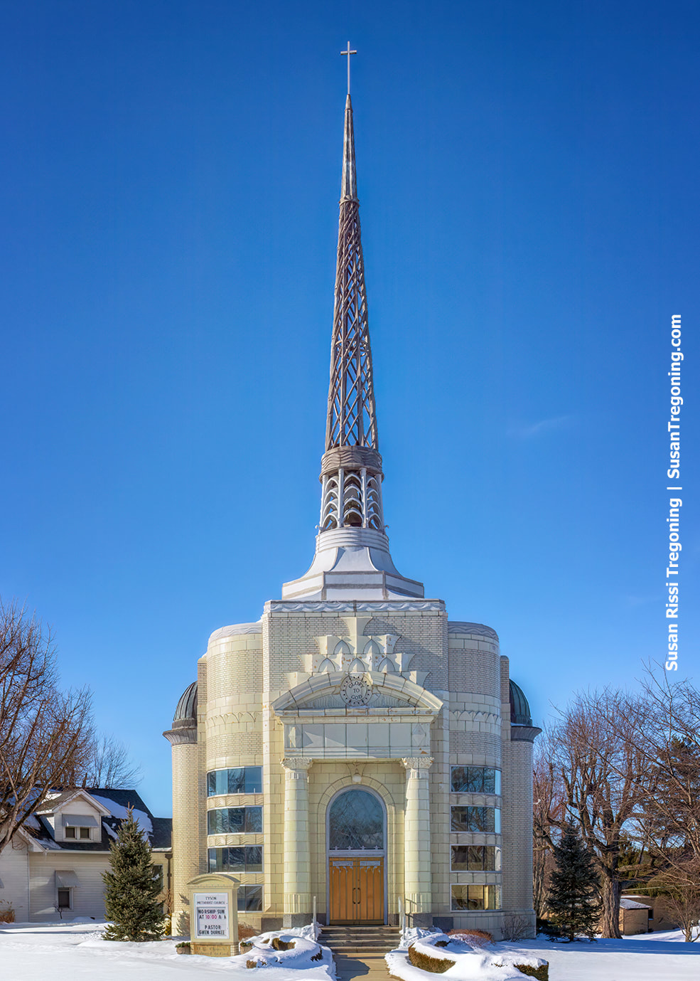 Art Deco Tyson Methodist Temple in Versailles, Indiana, built of glazed terracotta brick with a tall cast‑aluminum steeple, shown with snow on the ground.