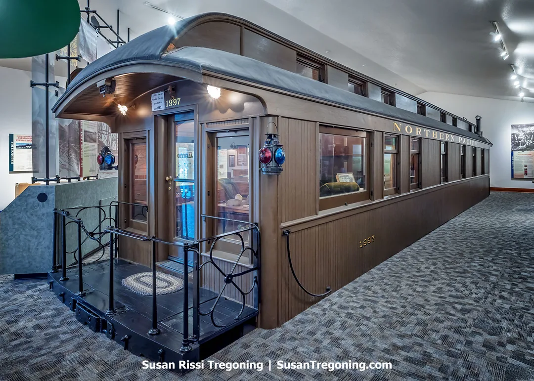 A historic 1881 Northern Pacific superintendent’s railcar, the Rosebud, displayed inside the Rosebud Visitor Center in Valley City, North Dakota. The restored railcar sits behind large windows, allowing visitors to look inside at its preserved wood interior and period furnishings.