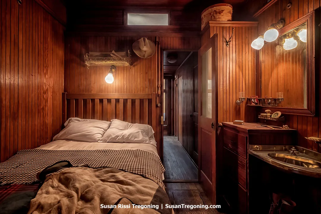 Interior of the 1881 Northern Pacific superintendent’s railcar “Rosebud,” showing a small sleeping area with wood‑paneled walls, a bed, and vintage fixtures that reflect 19th‑century railroad craftsmanship.