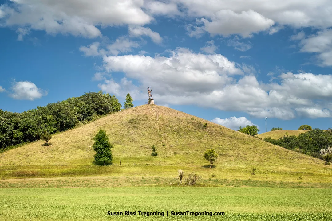 Pyramid Hill rises above the Sheyenne River Valley landscape, topped by a Viking statue that honors the area's Norwegian heritage beneath a sky filled with scattered clouds.