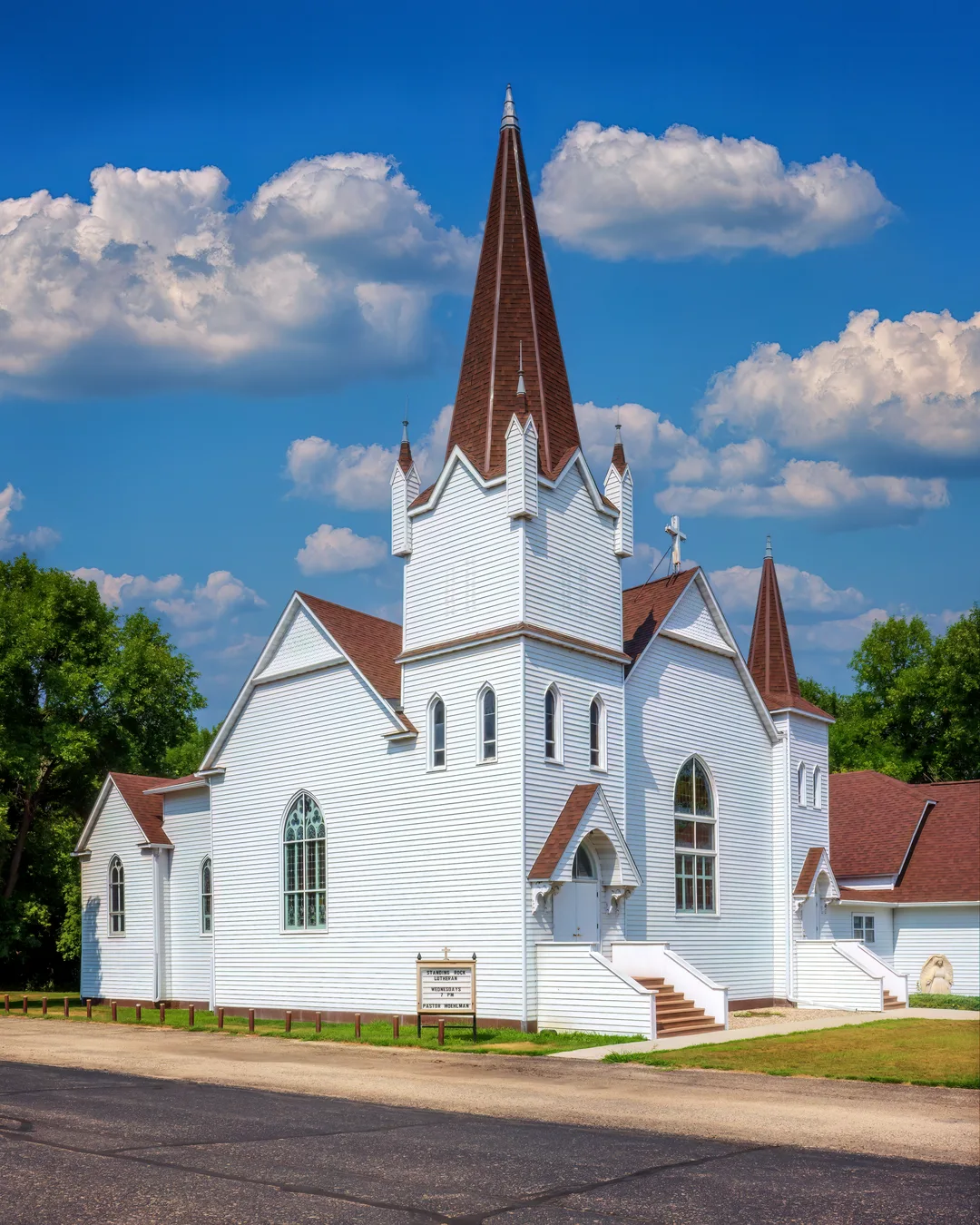 Historic white Standing Rock Lutheran Church with a tall steeple standing on a hillside near Fort Ransom, North Dakota, surrounded by open prairie and countryside in the Sheyenne River Valley.