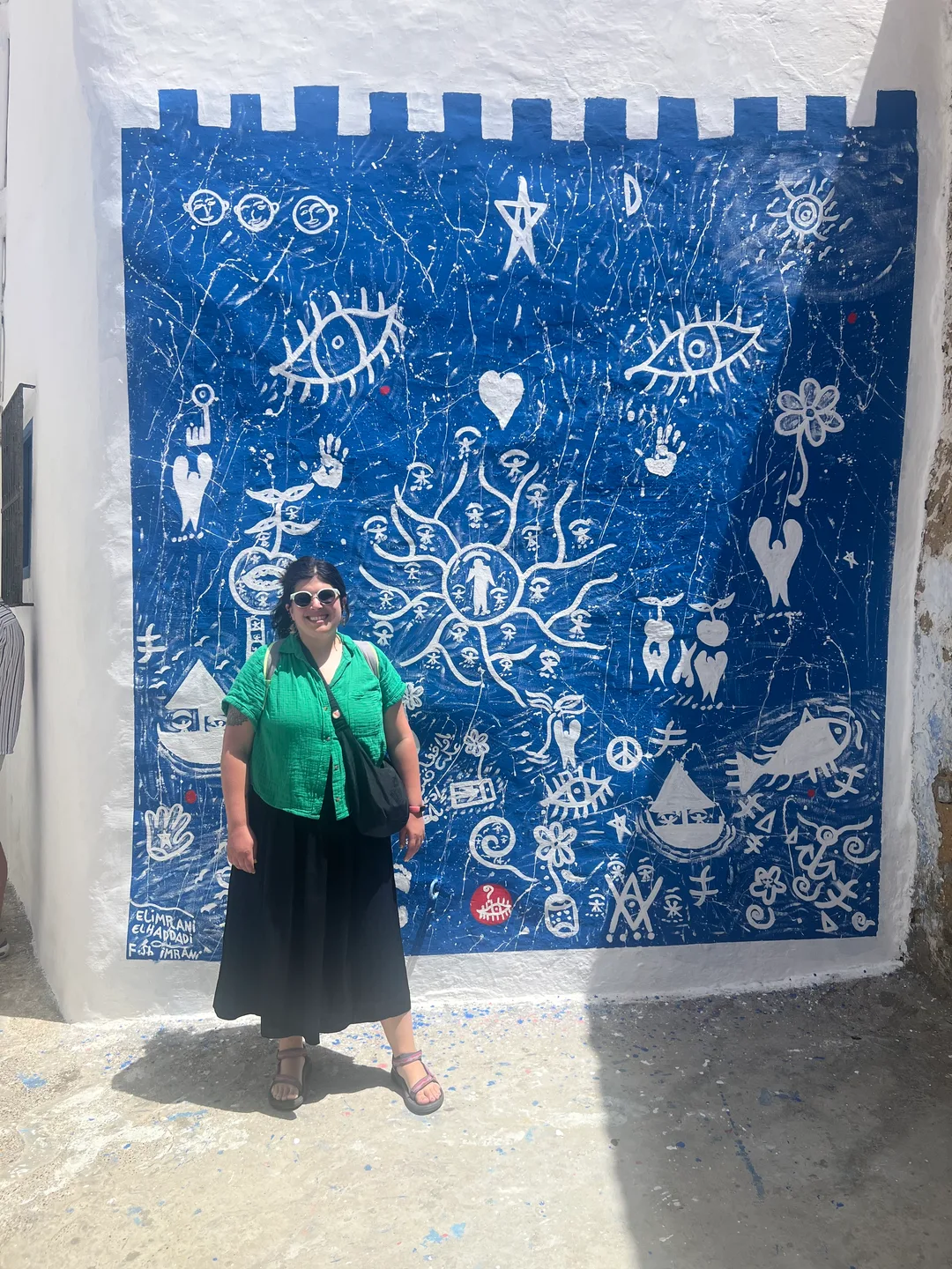 Photo of Gabi in front of a blue and white mural in the medina of Asilah, Morocco