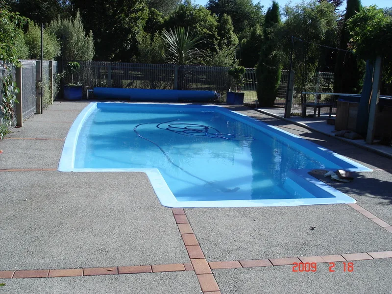 Rectangular fibreglass swimming pool beside a paved courtyard