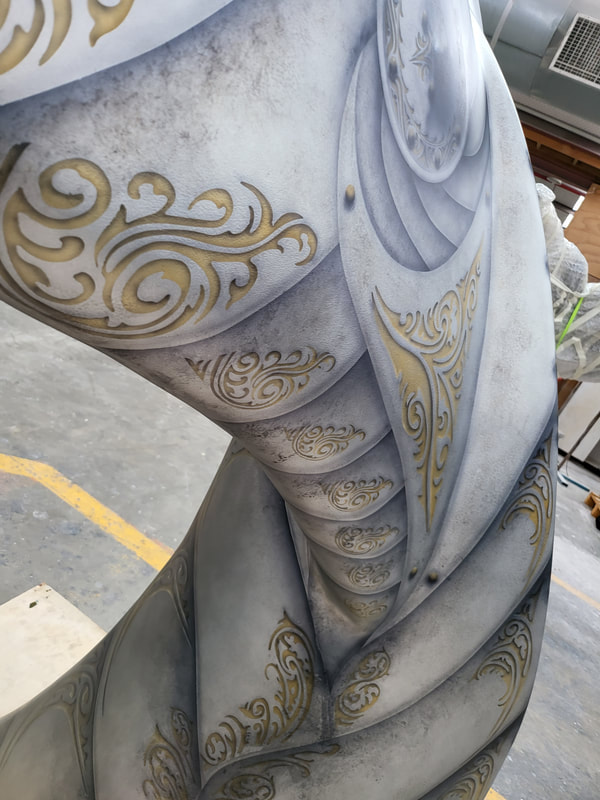 Close-up of the “Flukes of Steel” whale-tail sculpture with silver and gold artwork