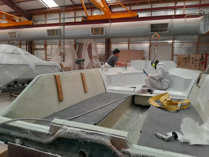 Worker laminating a large fibreglass boat mould