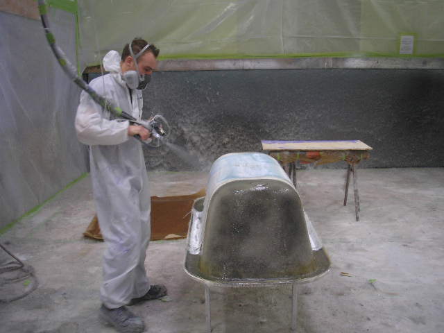 Worker applying resin to a composite bath with a chopper gun
