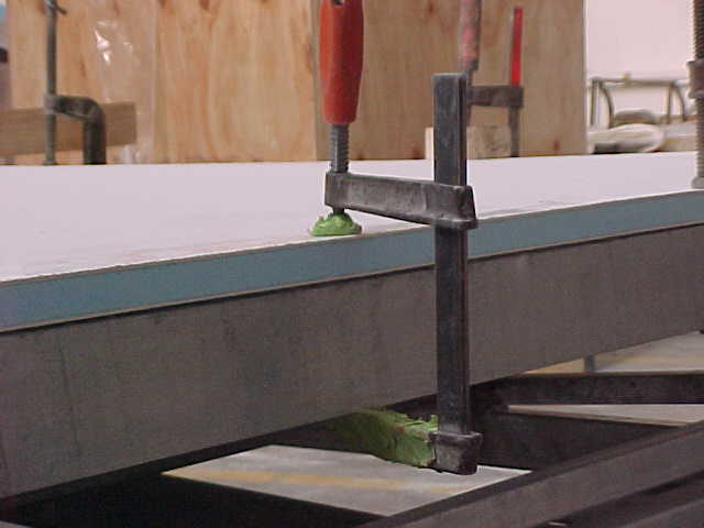 Floor panel clamped and bonded to the steel chassis