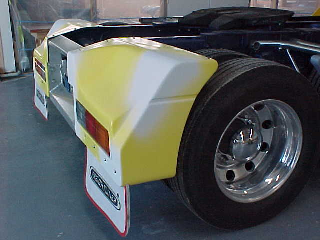 Yellow fibreglass rear body panel fitted beside the trailer wheels