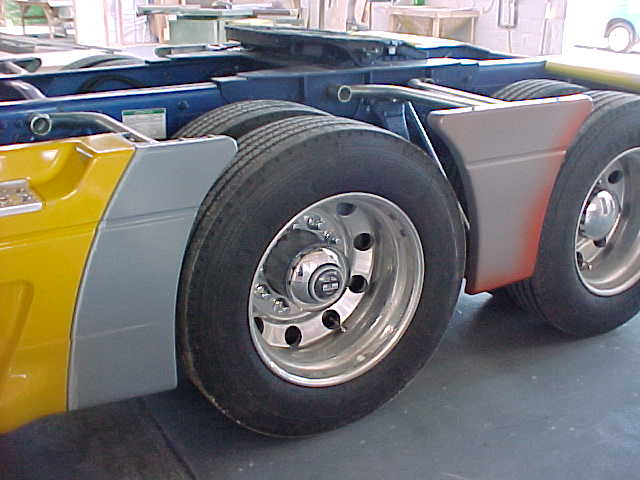 Yellow and grey fibreglass wheel-arch panel fitted to the mobile surgery trailer