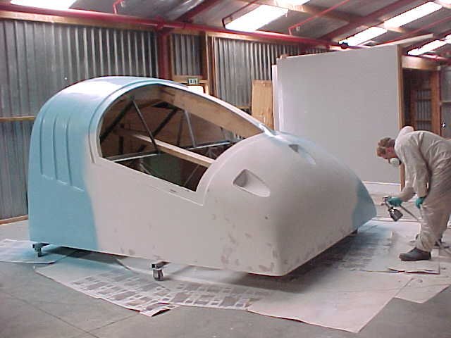 Worker sanding a moulded fibreglass trailer front in the workshop