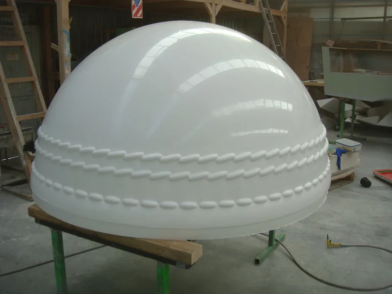 Moulded fibreglass cricket-ball half-shell resting on a work stand