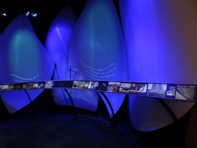 Blue-lit sail forms and exhibition display inside the Plastic Waka