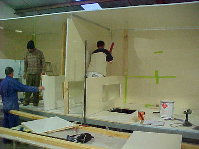 Workers installing interior wall and cubicle panels in the Super Loo