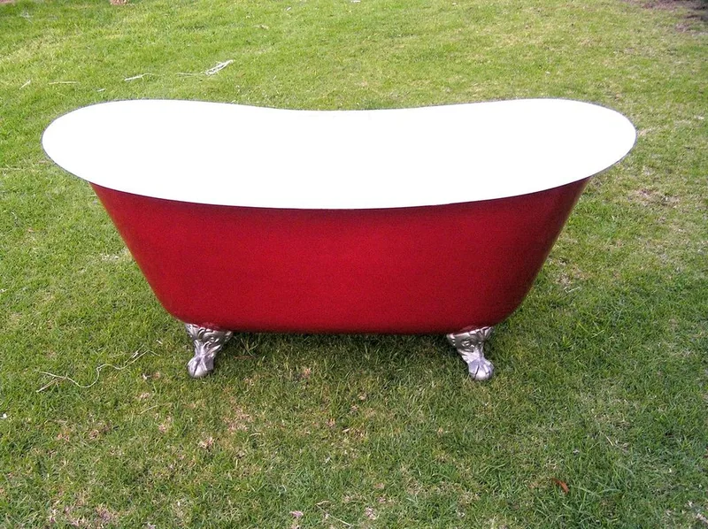 Red and white clawfoot composite bath on grass