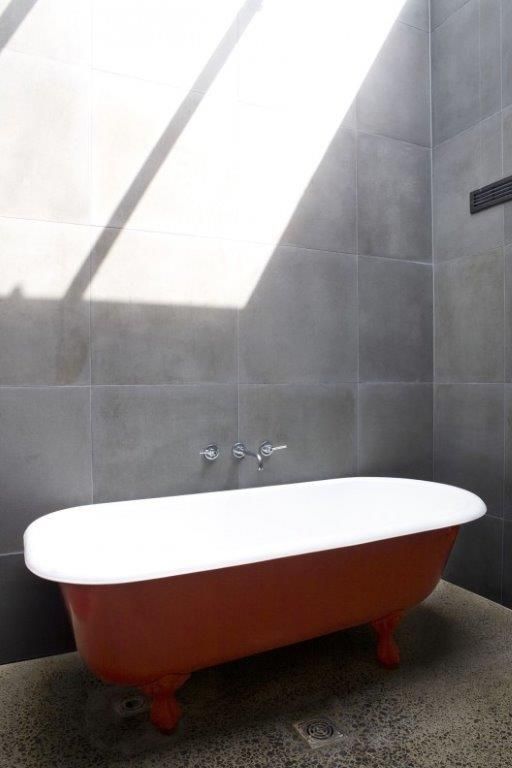 Red composite bath in a tiled bathroom