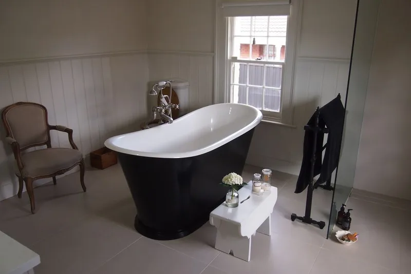 Black freestanding composite bath in a bedroom