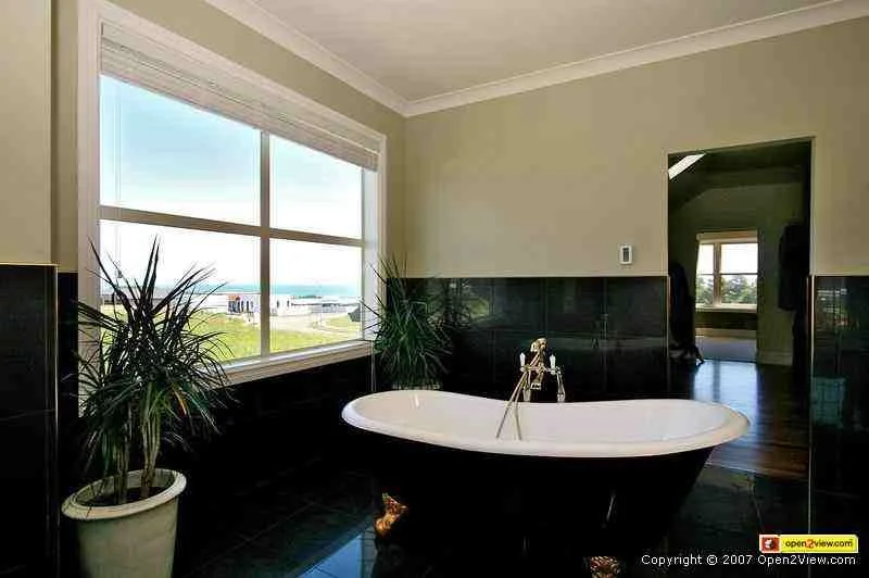 White slipper-style composite bath in a tiled bathroom