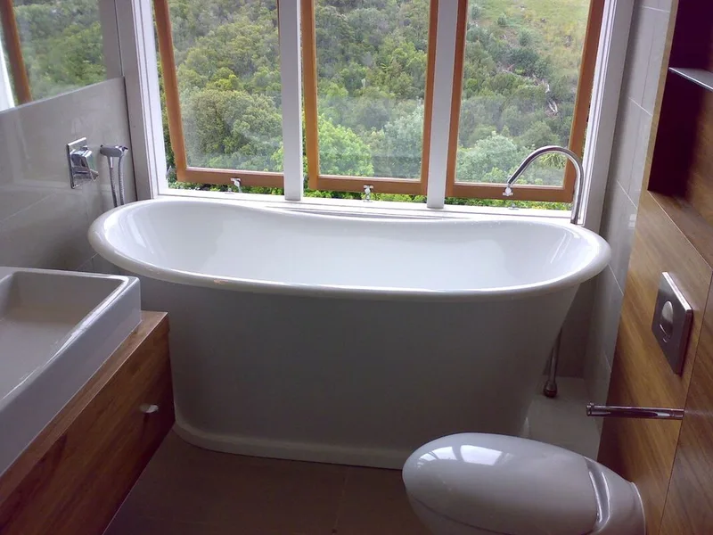 White freestanding bath beside large windows