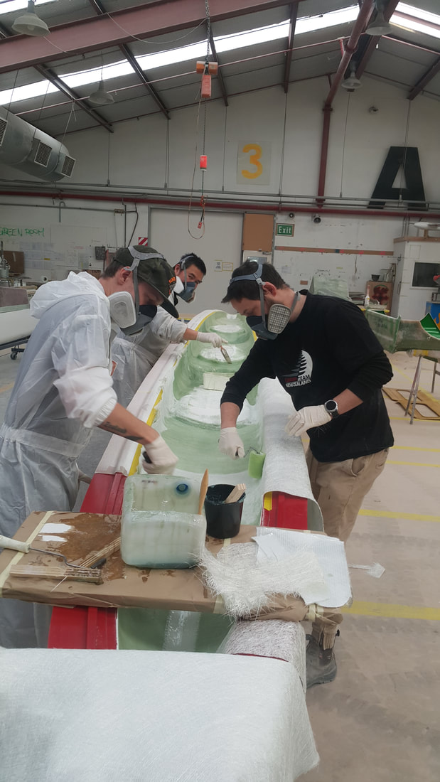 Workers hand-laminating a Holopuni canoe component