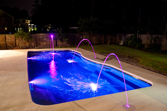 Swimming pool illuminated with purple underwater and feature lighting