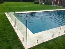 Frameless glass safety fence around an outdoor swimming pool