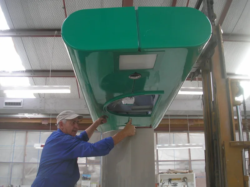 Worker guiding a green fibreglass BP truckstop component onto a forklift