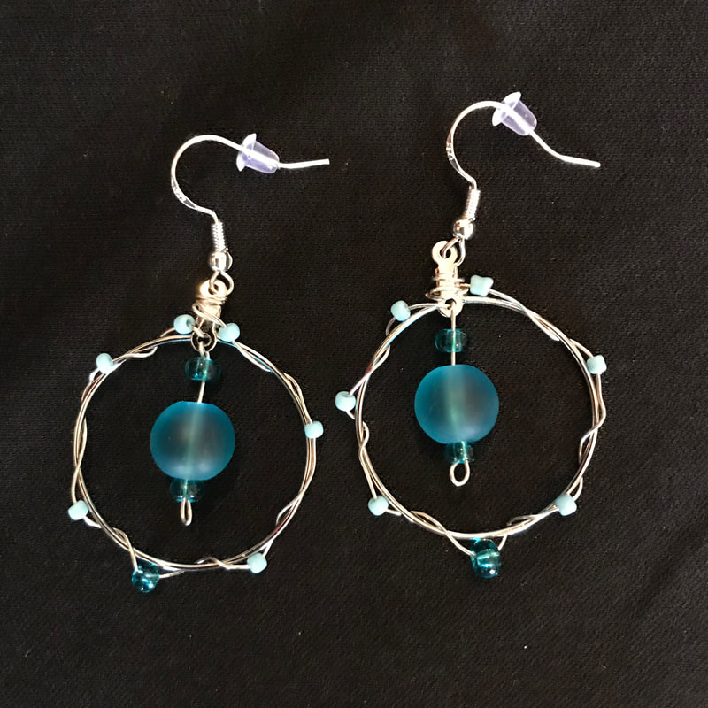 medium circle earrings a large blue bead in the center and smaller seeds beads wrapped around the earring
