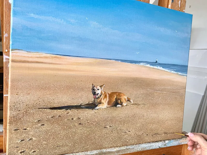 Portrait of a dog on its favorite beach with a lighthouse in the background and intricate footprints in the foreground.