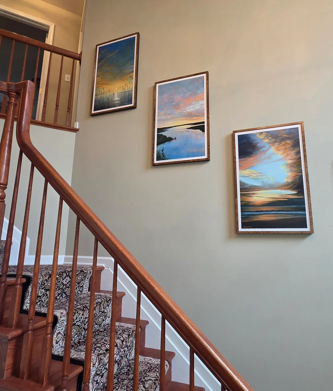 Photo of three custom canvas reproductions of Ellen Rice paintings arranged on client's wall and cathedral ceiling on stairs.