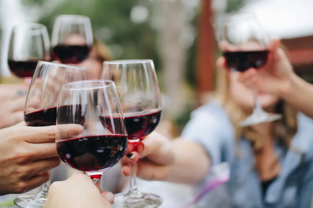Multiple people bringing their wine glasses together.