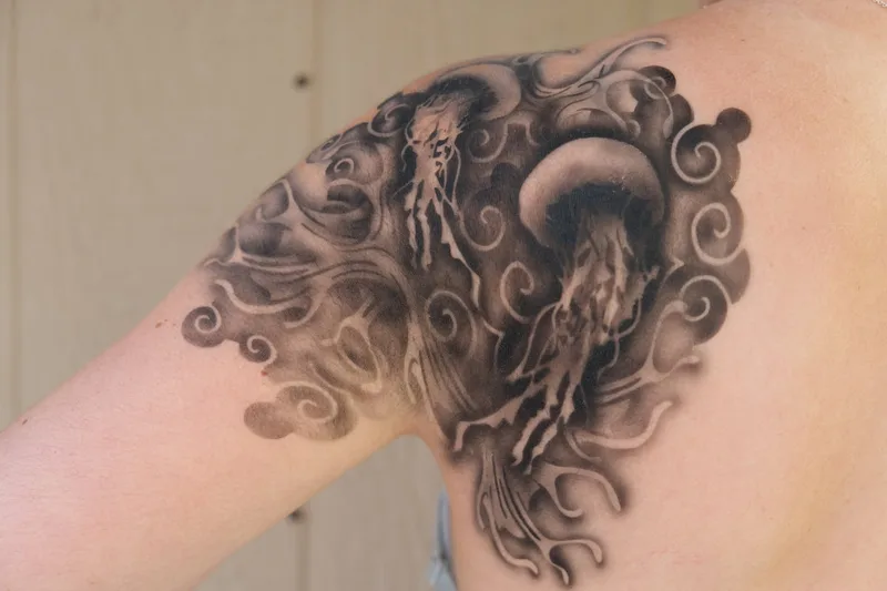 A light skinned person in the SF bay area models a realistic airbrush tattoo on their shoulder with jellyfish and waves in Mill Valley, California