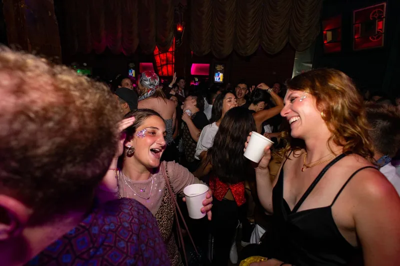 A group of young adults partying while wearing face paint and glitter at a disco in San Francisco