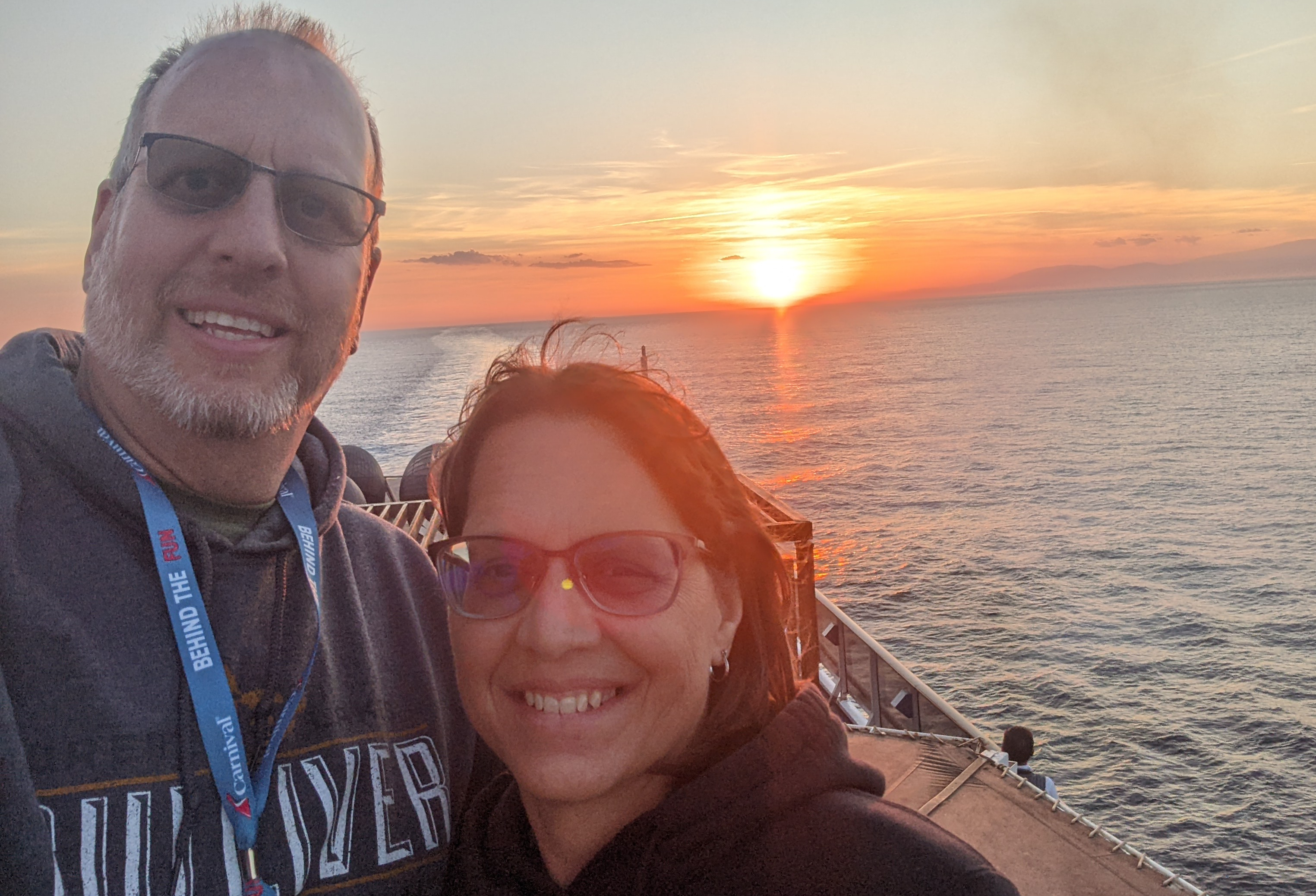 Bob and Lana Gates in front of a sunset on a cruise ship