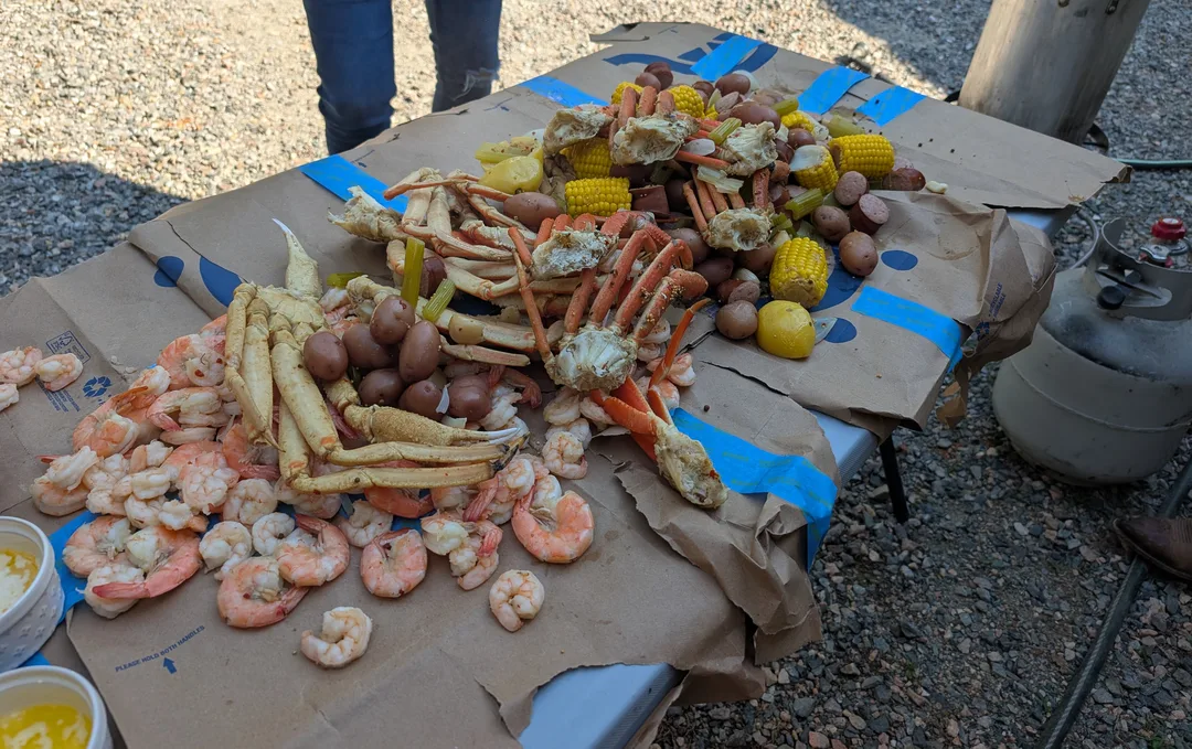 A seafood boil of crab legs, shrimp, corn, and potatoes on a table