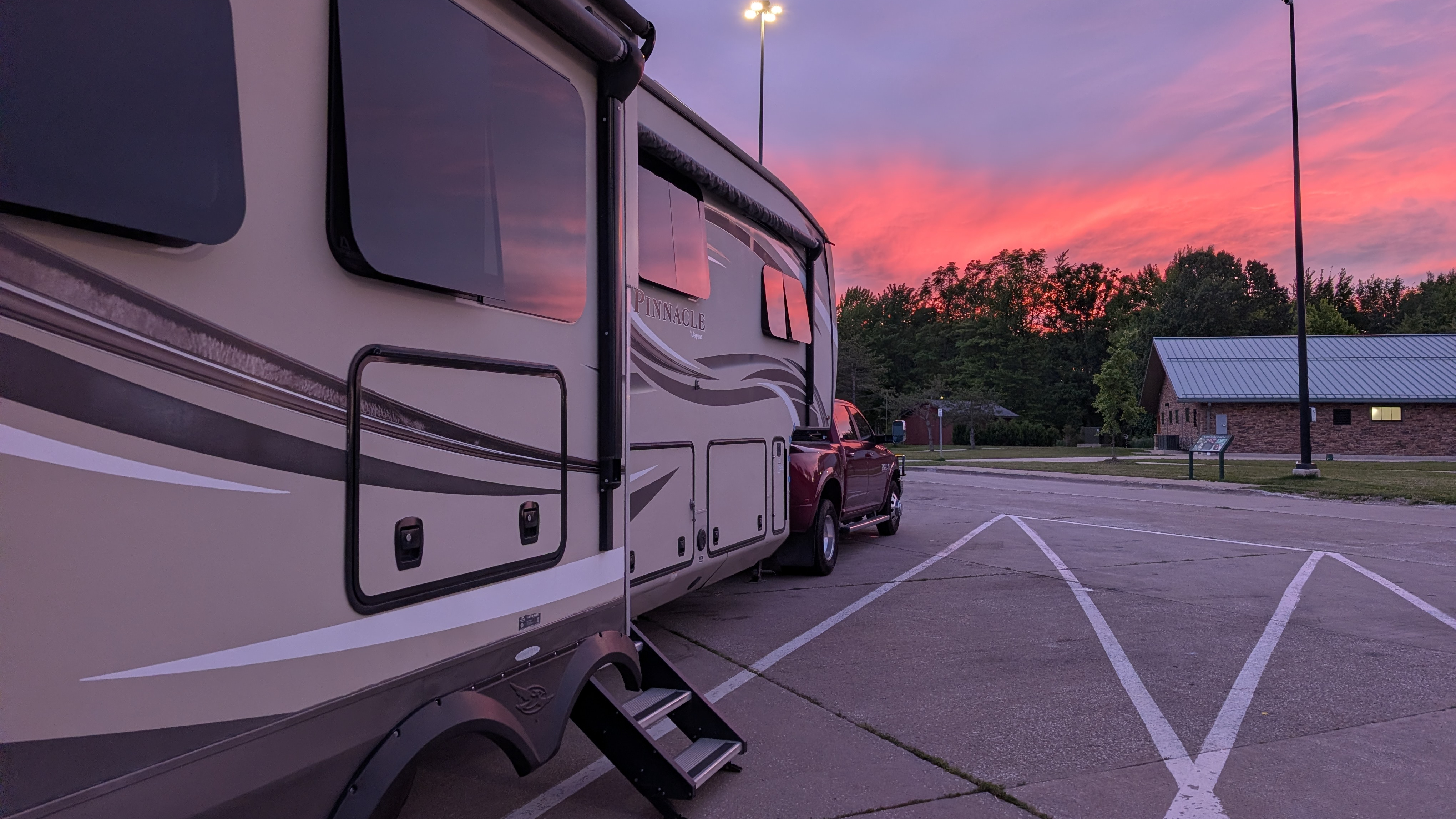 Fifth-wheel RV against a pink sky at sunset
