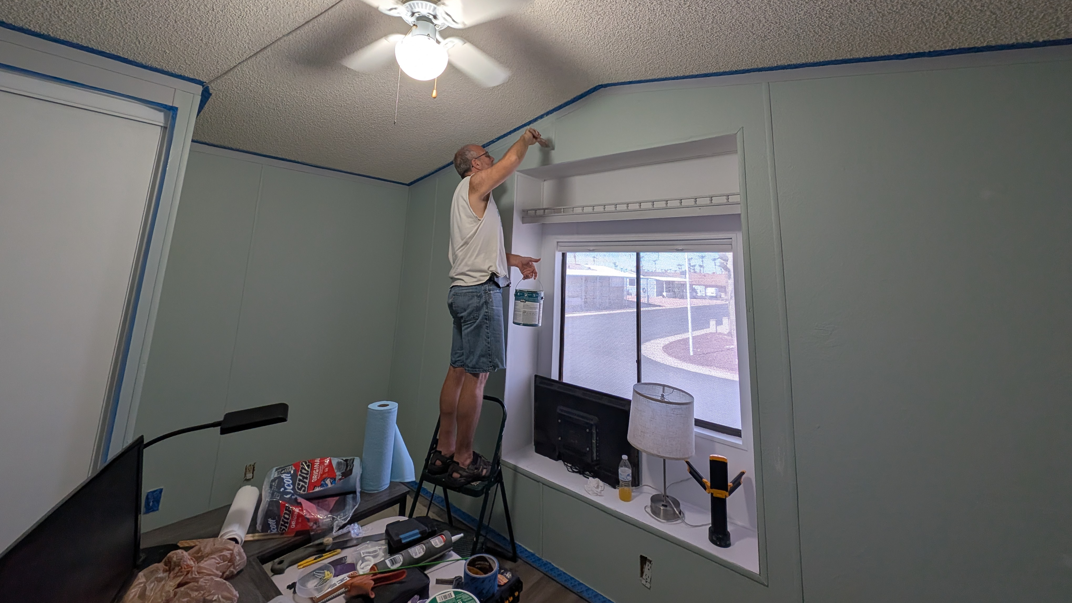 Man standing on a ladder painting an interior wall