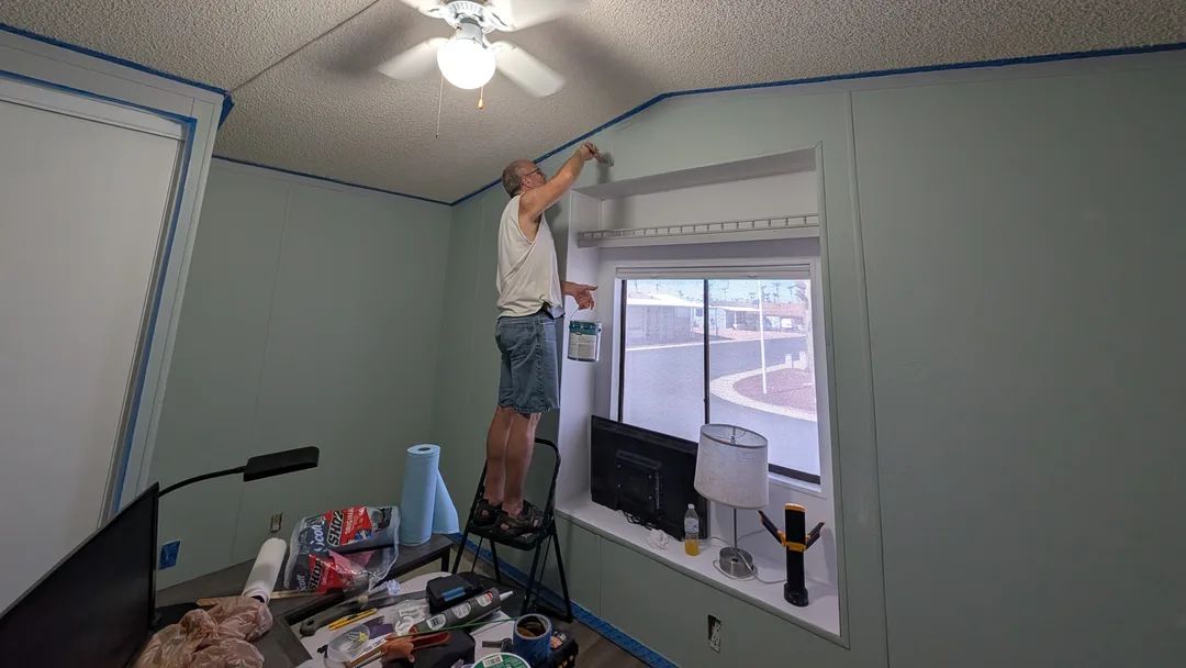 Man standing on a ladder painting an interior wall