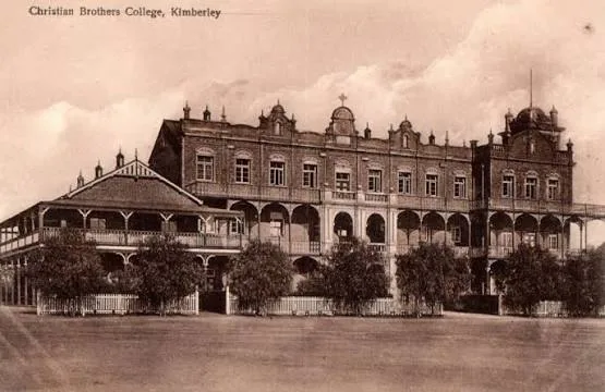 Historic sepia postcard showing Christian Brothers’ College Kimberley, with the long brick main building, arcaded verandas, tower and early campus structures.