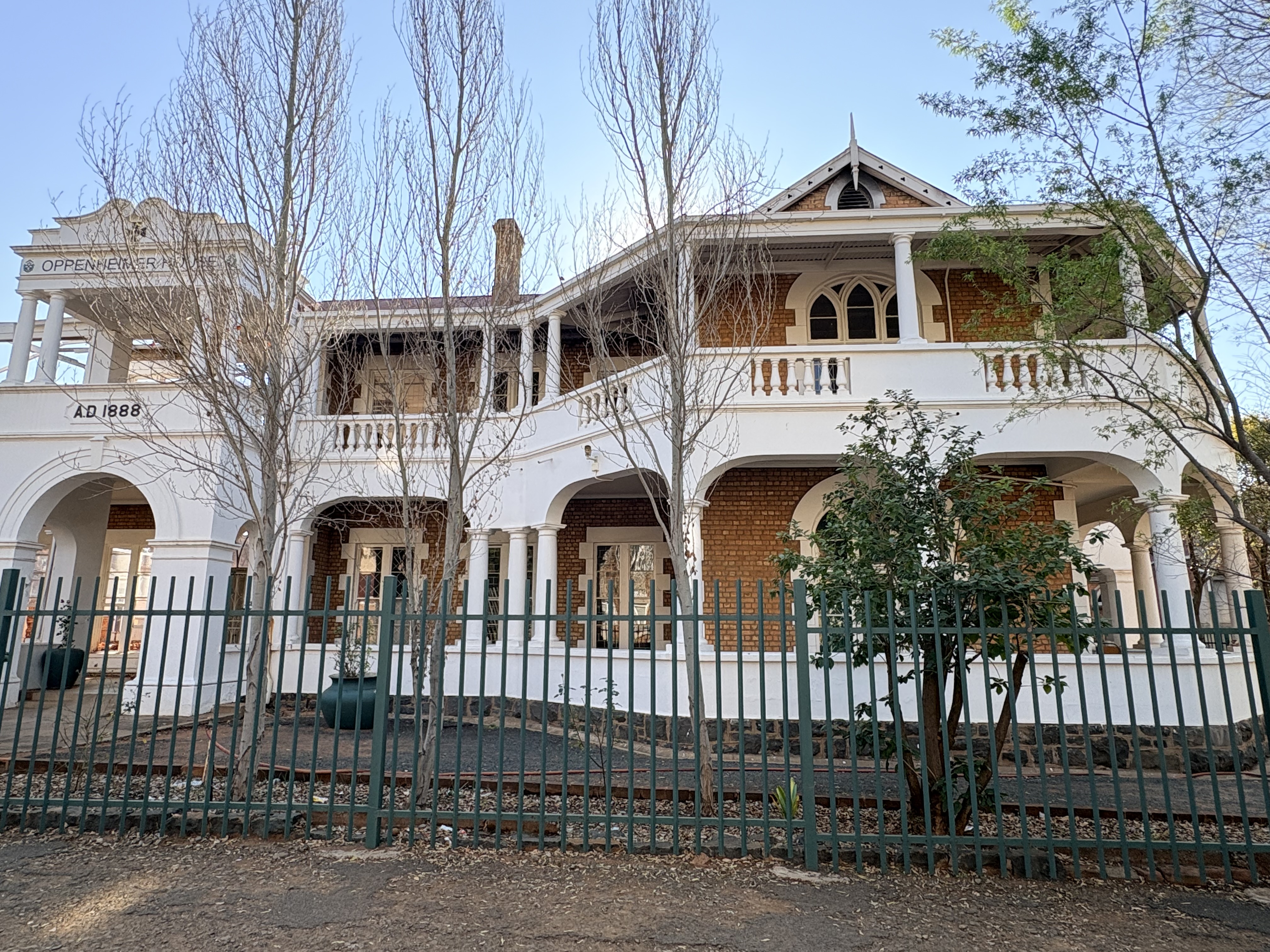 Oppenheimer House, formerly Nazareth House, viewed from Cornwall Road in Kimberley, showing its 1888 date, red-brick walls, white verandas, arches and columns.