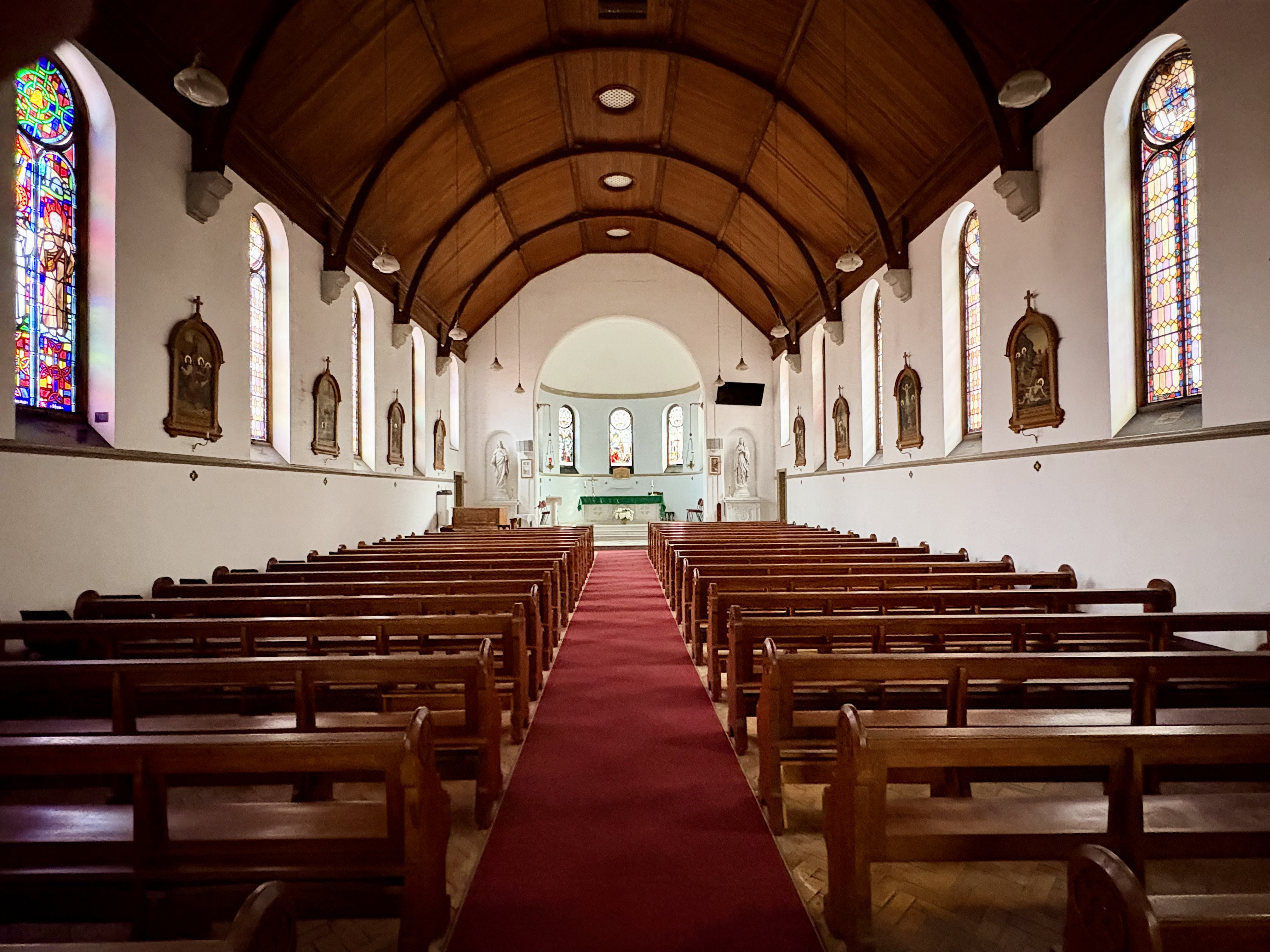 Interior of the College Chapel at St Patrick's CBC showing wooden pews, a central aisle, timber ceiling and stained-glass windows.