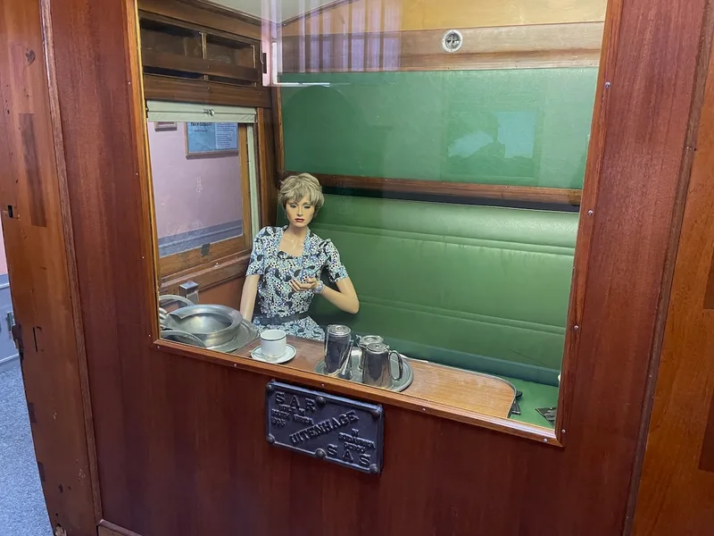 Preserved railway carriage compartment with upholstered seats, table and period railway tableware at the Kimberley Transport Museum. 